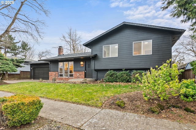 split level home featuring brick siding, a chimney, fence, a garage, and driveway