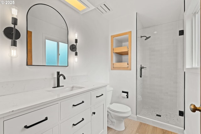 bathroom with toilet, vanity, a shower stall, and visible vents