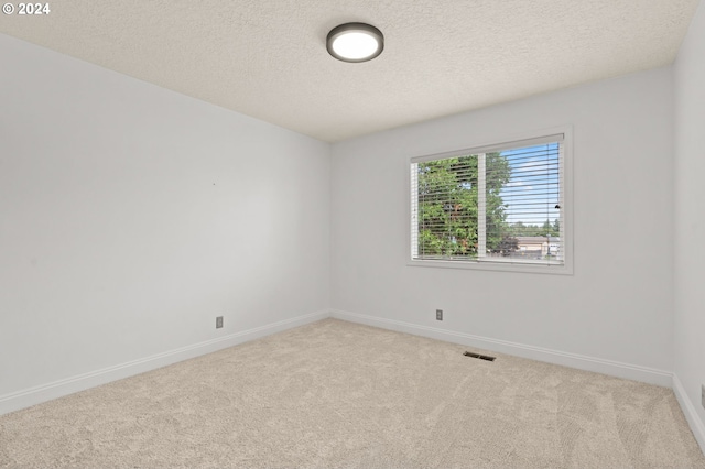 carpeted empty room featuring visible vents, a textured ceiling, and baseboards