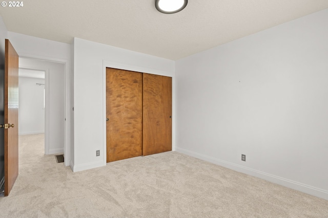 unfurnished bedroom featuring carpet, a closet, a textured ceiling, and baseboards