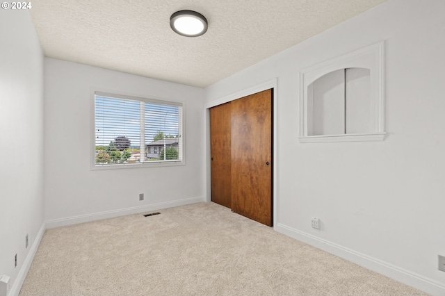 unfurnished bedroom with carpet, a closet, a textured ceiling, and baseboards