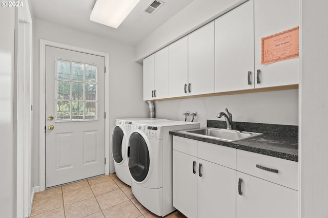 laundry area with cabinet space, light tile patterned floors, visible vents, washing machine and clothes dryer, and a sink