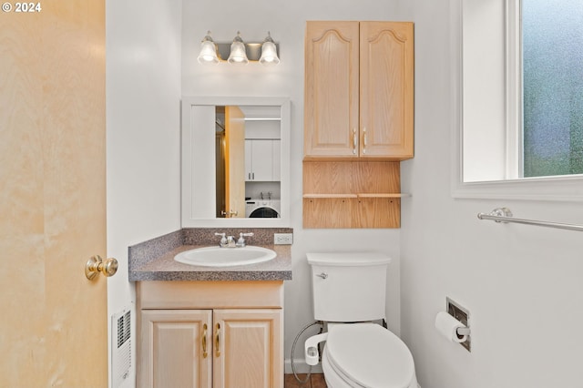 bathroom featuring toilet, washer / clothes dryer, and vanity