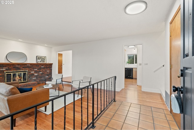 corridor featuring visible vents, light tile patterned flooring, an upstairs landing, and baseboards