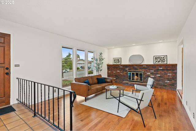 living area with recessed lighting, a brick fireplace, and light wood-style flooring