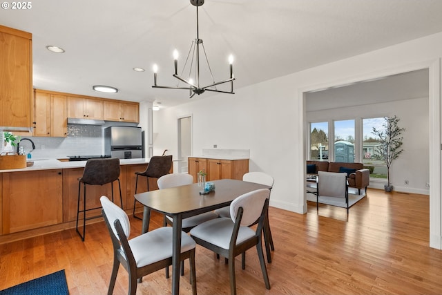 dining room with recessed lighting, light wood-style flooring, baseboards, and an inviting chandelier