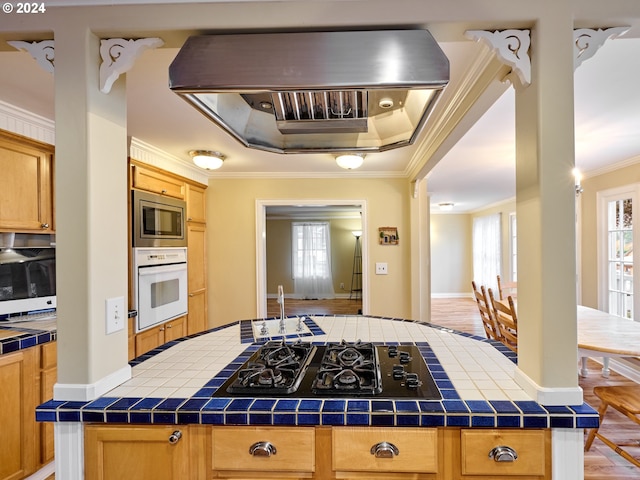 kitchen featuring tile countertops, black gas stovetop, crown molding, oven, and light wood-type flooring