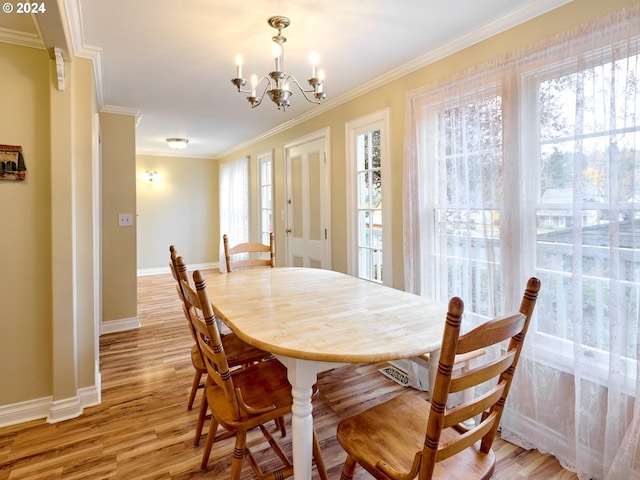 dining room featuring light hardwood / wood-style floors, crown molding, and a notable chandelier