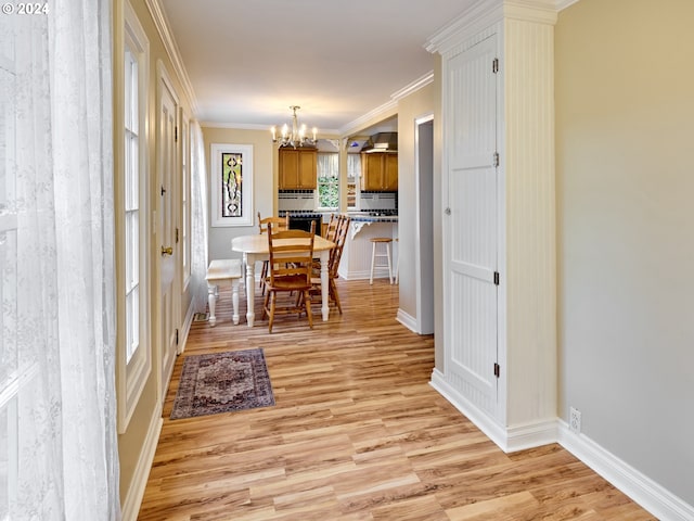 dining space with ornamental molding, light hardwood / wood-style floors, and a notable chandelier