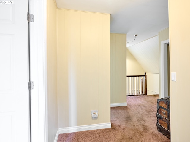 corridor with wooden walls, carpet floors, and lofted ceiling