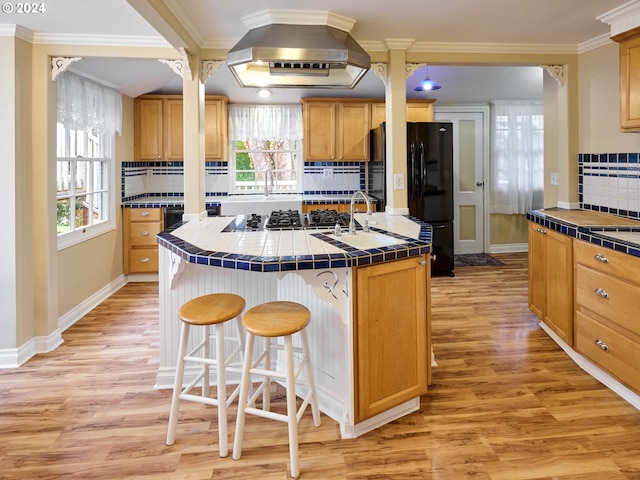 kitchen with an island with sink, tasteful backsplash, and tile counters