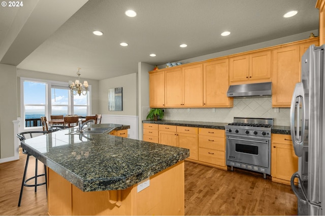 kitchen featuring appliances with stainless steel finishes, dark hardwood / wood-style flooring, sink, a breakfast bar area, and a center island with sink