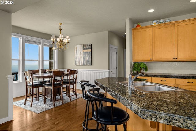 kitchen featuring an inviting chandelier, hardwood / wood-style floors, sink, a water view, and a kitchen breakfast bar