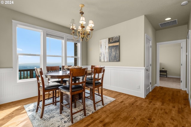 dining area with wood-type flooring and a notable chandelier