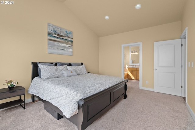 bedroom with lofted ceiling, light colored carpet, and ensuite bath