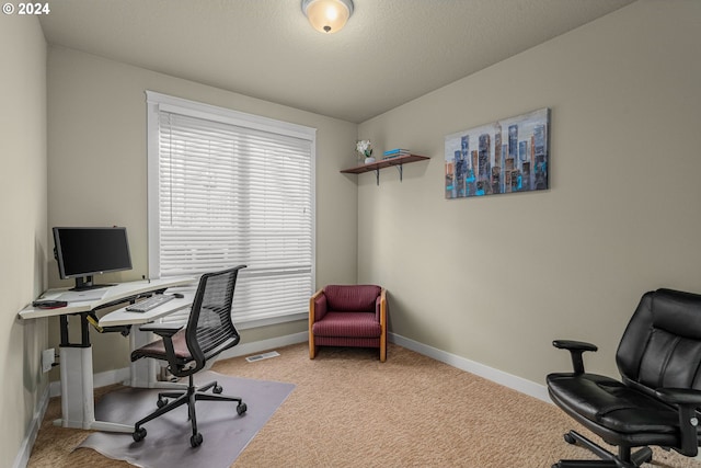 carpeted home office featuring a textured ceiling