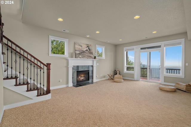 unfurnished living room with a textured ceiling, carpet floors, and a fireplace