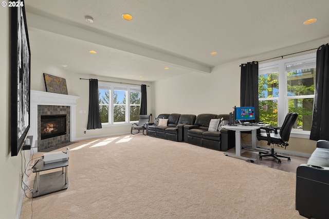 living room with a tiled fireplace, beamed ceiling, and carpet flooring