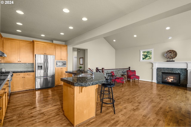 kitchen with stainless steel appliances, dark hardwood / wood-style flooring, a kitchen island, sink, and a breakfast bar