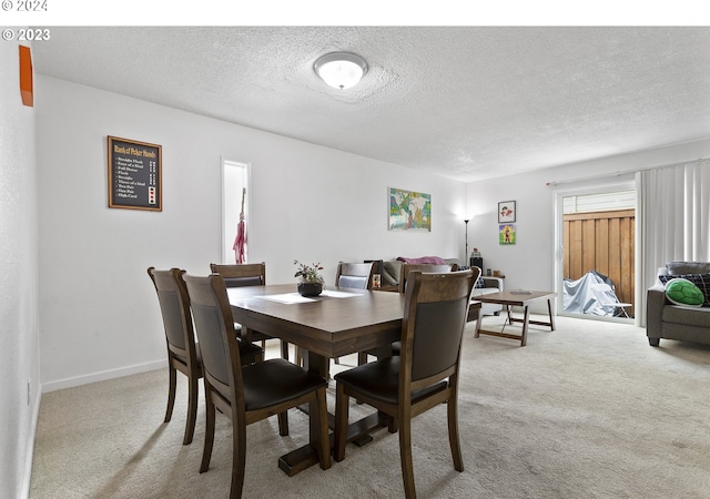 carpeted dining room featuring a textured ceiling