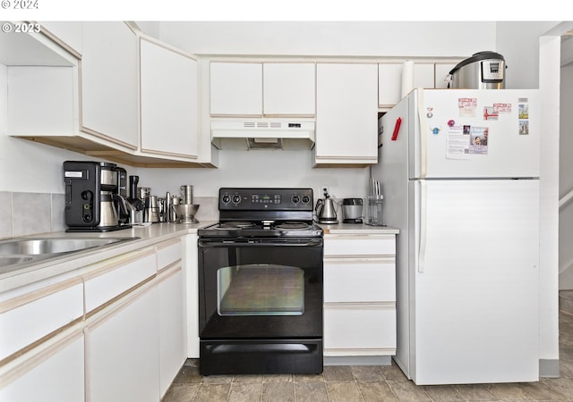 kitchen featuring black / electric stove, white cabinetry, and white fridge