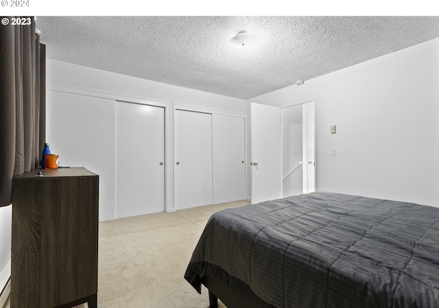 carpeted bedroom featuring a textured ceiling and two closets