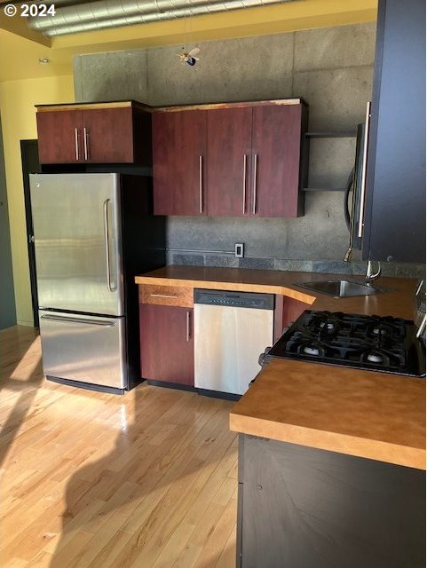 1410 SW 11th Ave Unit 402, Portland, OR 97201 - kitchen with light wood-style floors, a sink, open shelves, and stainless steel appliances