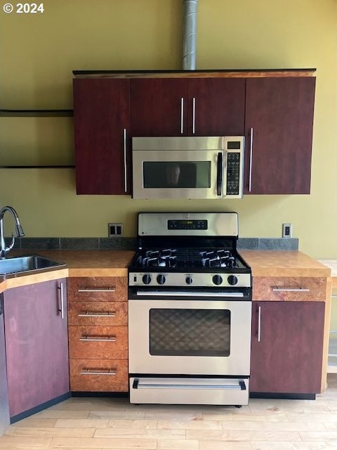 kitchen with white gas stove, sink, and light wood-type flooring