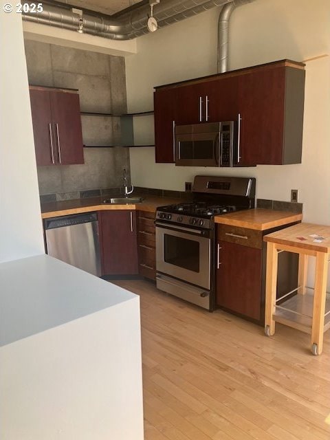 1410 SW 11th Ave Unit 402, Portland, OR 97201 - kitchen featuring appliances with stainless steel finishes, light wood-style floors, and dark brown cabinetry