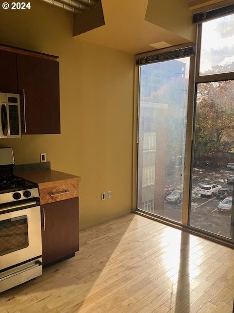 kitchen featuring a wall of windows, light wood-type flooring, and white range oven