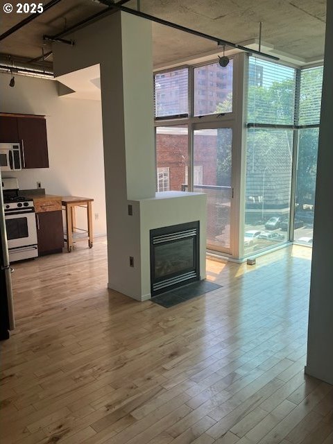 1410 SW 11th Ave Unit 402, Portland, OR 97201 - unfurnished living room featuring a wall of windows, light wood-style flooring, and a fireplace with flush hearth