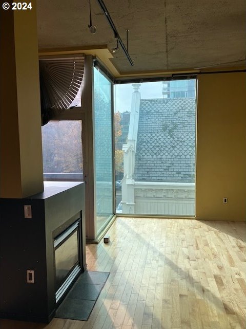 1410 SW 11th Ave Unit 402, Portland, OR 97201 - entryway with rail lighting, a fireplace with flush hearth, a healthy amount of sunlight, and hardwood / wood-style floors