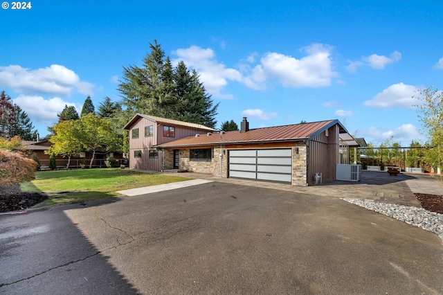 view of front of property with a front yard, a garage, and central AC unit