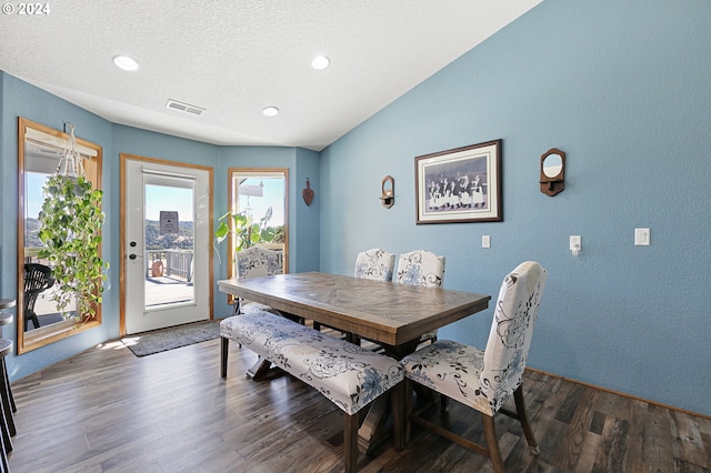 dining area featuring a textured ceiling, dark wood-type flooring, and lofted ceiling