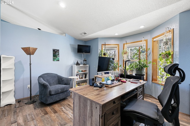 office area featuring lofted ceiling, light hardwood / wood-style flooring, and a textured ceiling