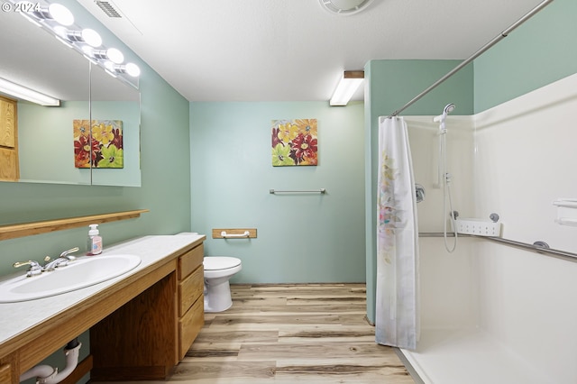 bathroom featuring walk in shower, vanity, wood-type flooring, and toilet