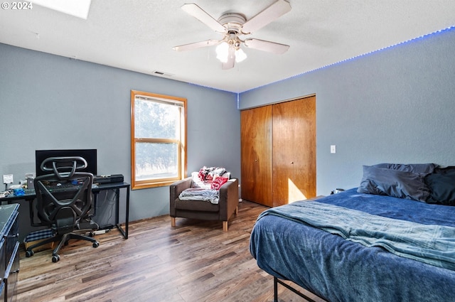 bedroom with ceiling fan, a closet, a textured ceiling, and hardwood / wood-style flooring