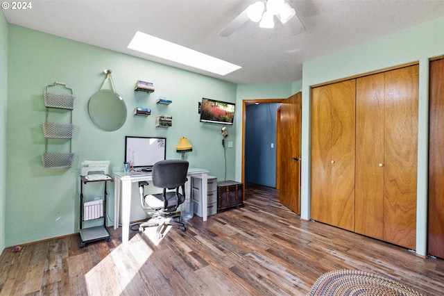 home office with ceiling fan, dark wood-type flooring, and a skylight