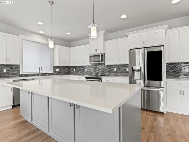 kitchen with stainless steel appliances, hanging light fixtures, a center island, and white cabinets