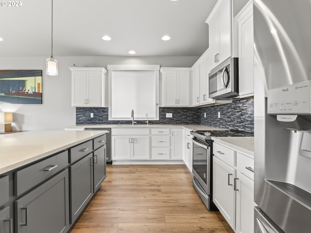 kitchen with sink, gray cabinetry, hanging light fixtures, appliances with stainless steel finishes, and white cabinets