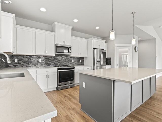 kitchen with white cabinetry, appliances with stainless steel finishes, sink, and a center island