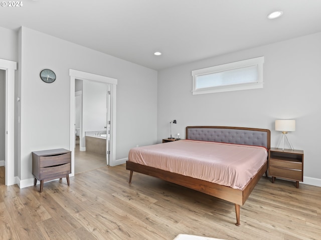 bedroom with connected bathroom and light hardwood / wood-style flooring