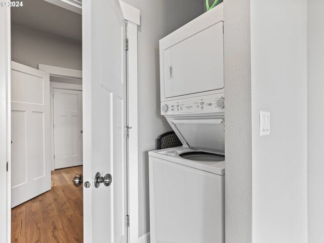 laundry area featuring stacked washer and dryer and hardwood / wood-style floors