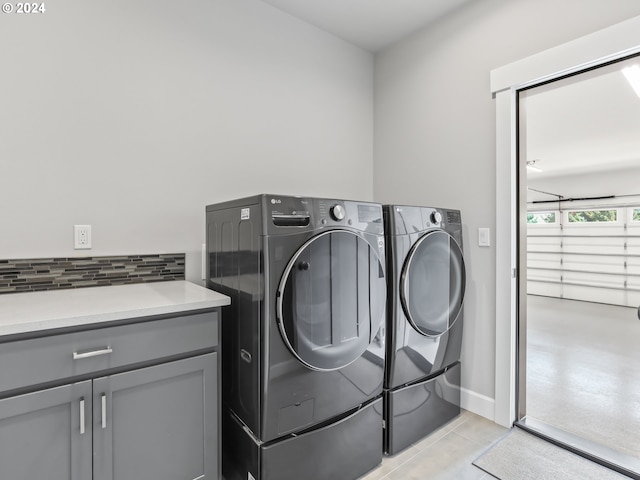 laundry room featuring washing machine and dryer, cabinets, and light tile patterned flooring