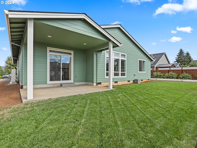 back of house with a lawn and a patio