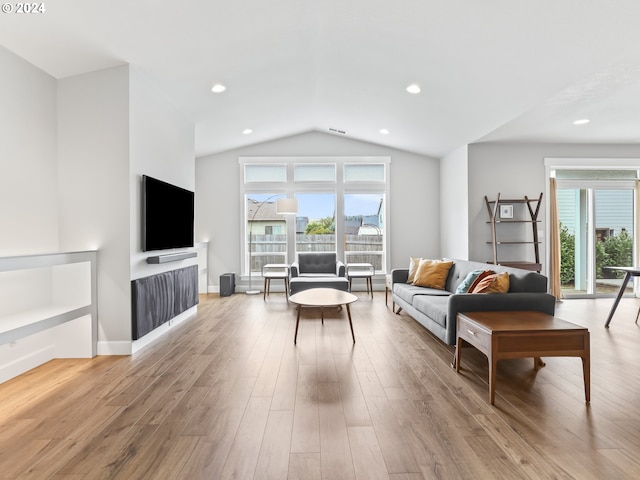 living room with plenty of natural light, vaulted ceiling, and light wood-type flooring