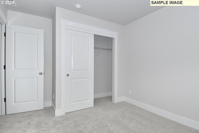 unfurnished bedroom featuring a closet and light colored carpet