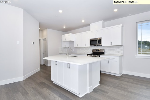 kitchen featuring white cabinets, sink, a center island with sink, appliances with stainless steel finishes, and hardwood / wood-style floors