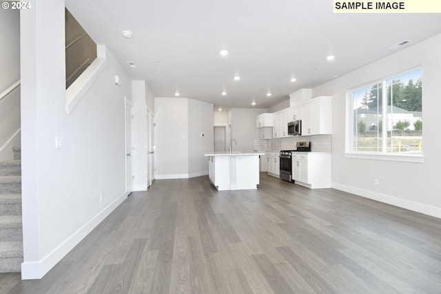 kitchen with white cabinets, sink, a center island with sink, light hardwood / wood-style flooring, and stainless steel appliances