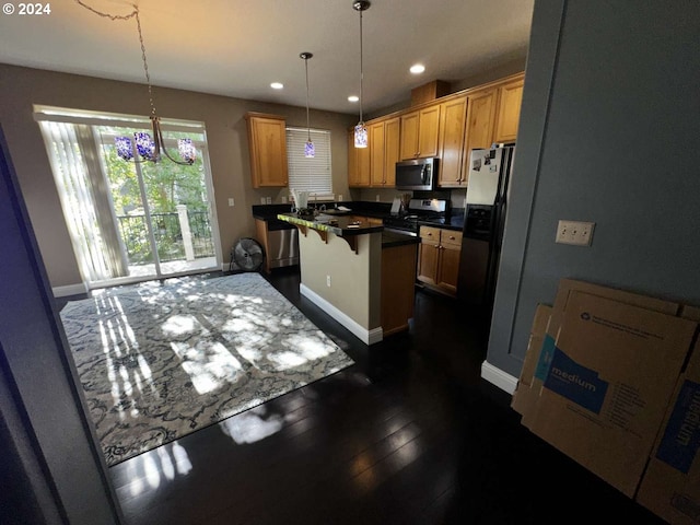 kitchen with pendant lighting, a kitchen island, dark wood-type flooring, stainless steel appliances, and a breakfast bar area